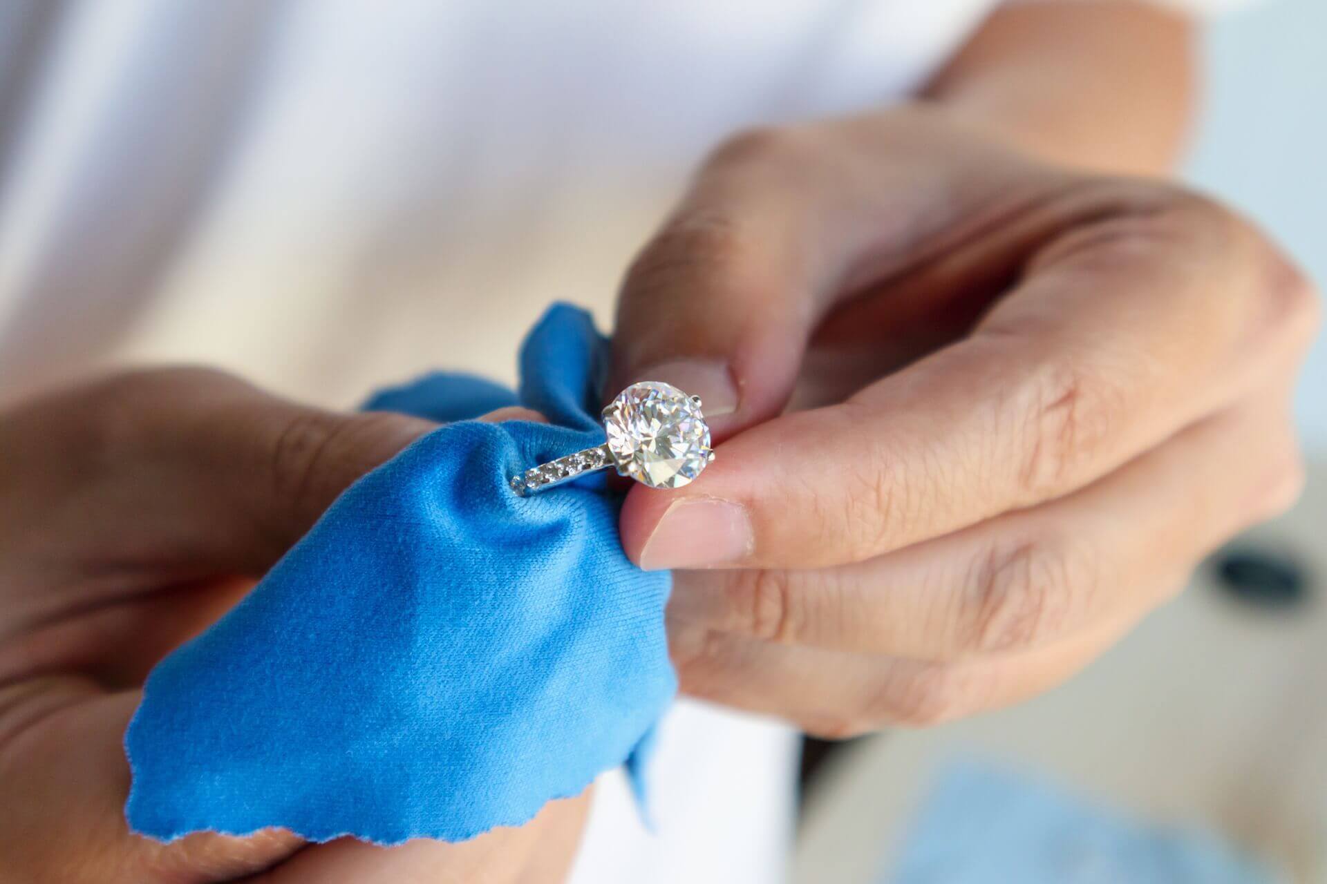 Mano con anello che pulisce con un panno azzurro